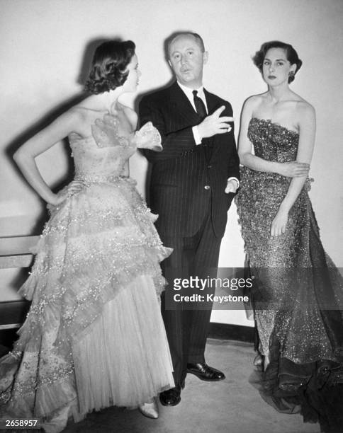 Fashion designer Christian Dior with two models wearing his creations.