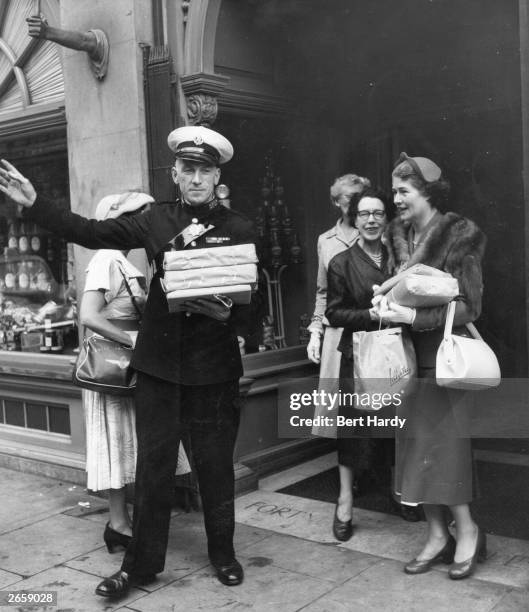 Commissionaire hails a taxi for customers at Fortnum and Mason's store in Piccadilly, London.