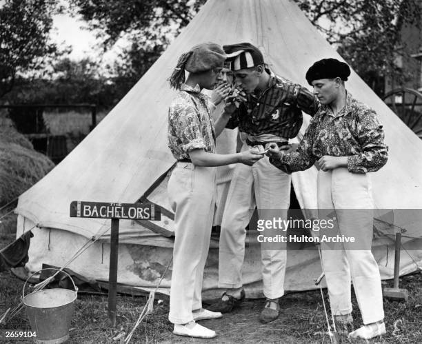 Four fashionable young men having a smoke outside their tent.