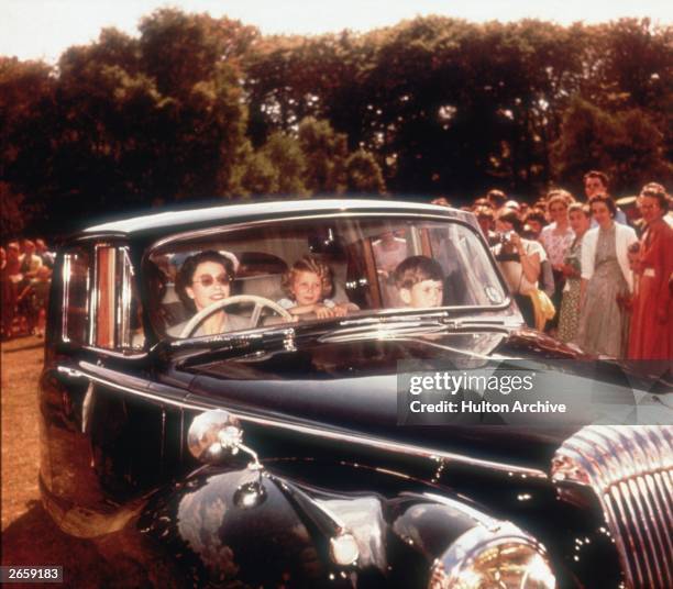 Queen Elizabeth II driving a Daimler saloon car with Prince Charles and Princess Anne as passengers, circa 1957.