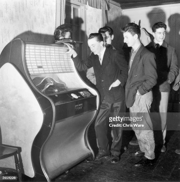 Two teenage boys listening to the latest hits on a pub jukebox.