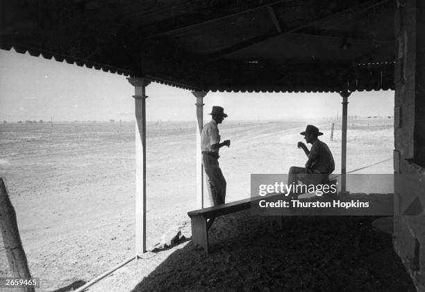 Two men having a drink in a shady corner of the Australian outback. Original Publication: Picture Post - 6832 - Cattle Stockman - Australia - unpub.