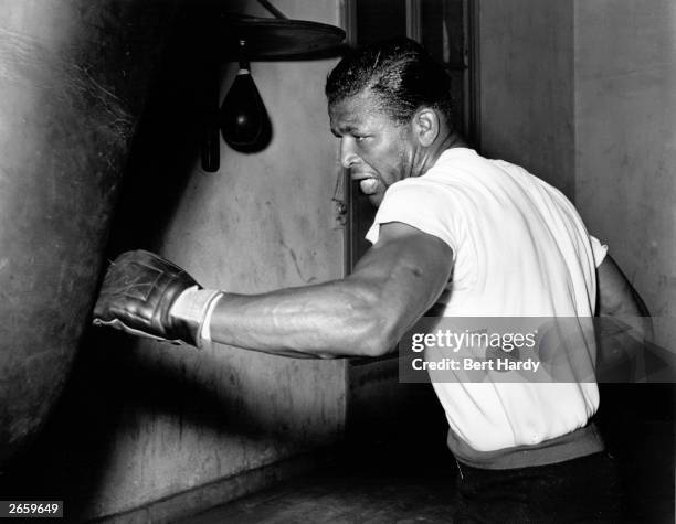 American boxer Sugar Ray Robinson in training with a punch bag at Roger Oquinarenne's gymnasium in Paris for his world middleweight fight against...