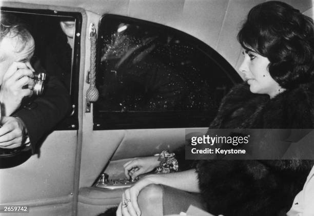 Actress Elizabeth Taylor as she arrives in Paris. A determined paparazzo can be seen taking a shot through the car window.
