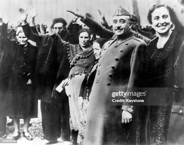 Spanish military dictator General Francisco Franco and his wife Dona Carmen Polo are saluted at a reception at Burgos to award the parents of large...