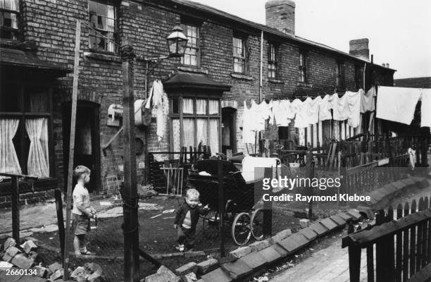 Two children playing in the back garden of their house in Salford. Original Publication: Picture Post - 8127 - The Housing Jungle - pub. 1955