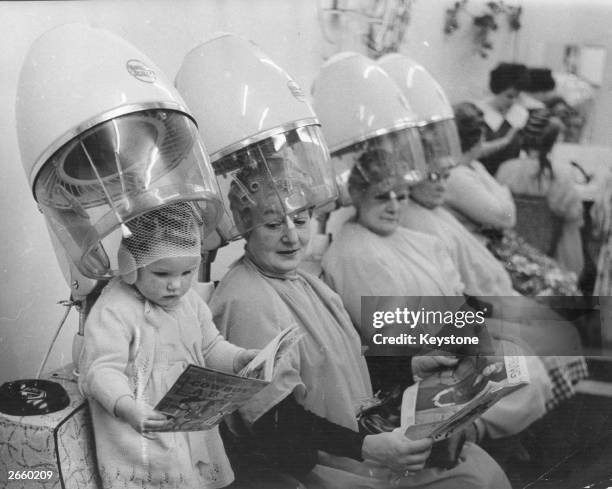 Child joins the older ladies under the hairdryers at the hairdressers.
