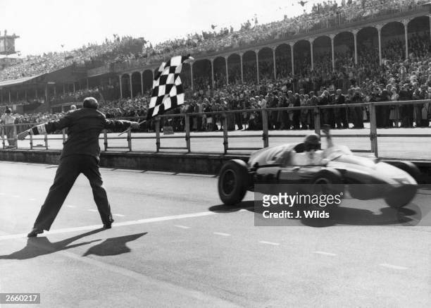 Racing driver Jack Brabham takes the checkered flag in his Cooper-Climax, to win the British Grand Prix at Aintree,18th July 1959.
