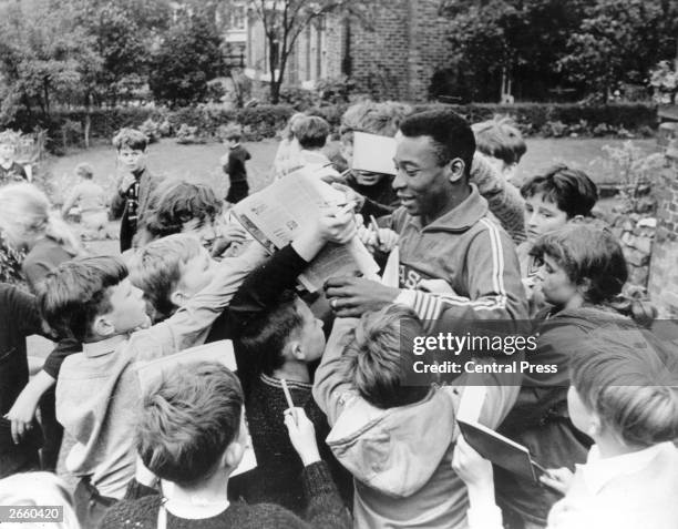 Brazilian footballer Pele, surrounded by young autograph hunters.