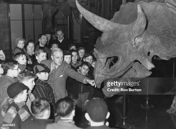 Dr W E Swinton taking a lesson at the National History Museum in London, with the aid of a Triceratops Prorsus.