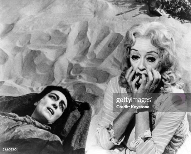 Actresses Joan Crawford and Bette Davis lie on the sand in a scene from the film 'Whatever Happened to Baby Jane?', directed by Robert Aldrich.