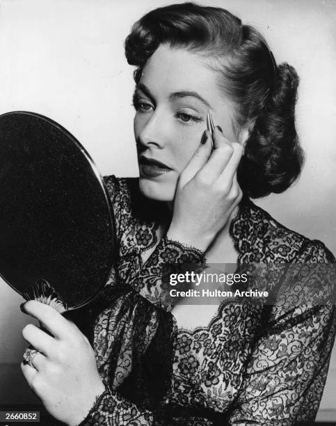 American actress Eleanor Parker plucks her eyebrows as part of her beauty routine for the film 'Chain Lightning', directed by Stuart Heisler for...