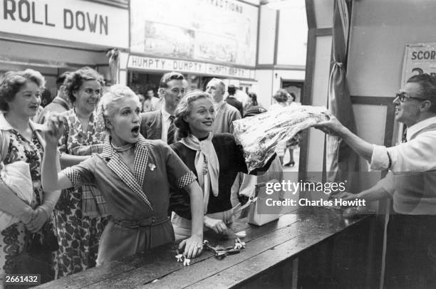 Austrian coloratura soprano, Josette Adrienne, appearing at the Grand Theatre, Brighton, spends some free time playing darts on a fairground stall on...