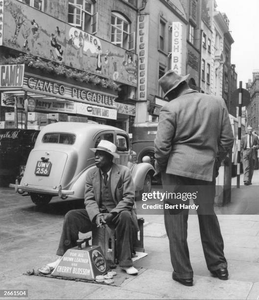 Shoe shiner in Piccadilly, London, waits for customers. Original Publication: Picture Post - 6576 - What Makes Piccadilly - pub. 1953