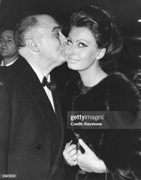 Italian film producer Carlo Ponti kisses his wife, actress Sophia Loren after she received the first Alexander Korda award, naming her 'International...