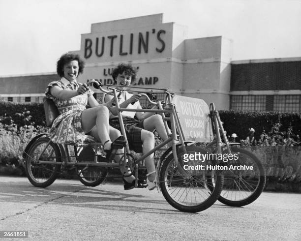 Two holidaymakers riding a bicycle for two at Butlin's Holiday Camp in Clacton.