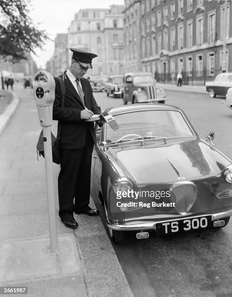 Traffic warden writing out a ticket for a car which had not paid the parking fee on the parking meter scheme in Mayfair, London.