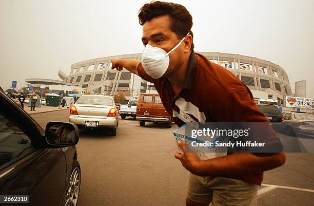 Volunteer Joe Enrique helps guide evacuees into the parking lot at Qualcomm Stadium October 27, 2003 in San Diego, California. Evacuees from around...