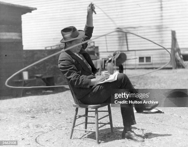 Will Rogers , American rustic comedian playing with a lasso whilst writing himself some notes, 1920. Original Publication: People Disc - HK0481