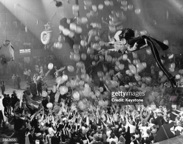 Huge caricature of conductor Sir Malcolm Sargent floating above the crowd of New Year revellers at the Chelsea Arts Ball.