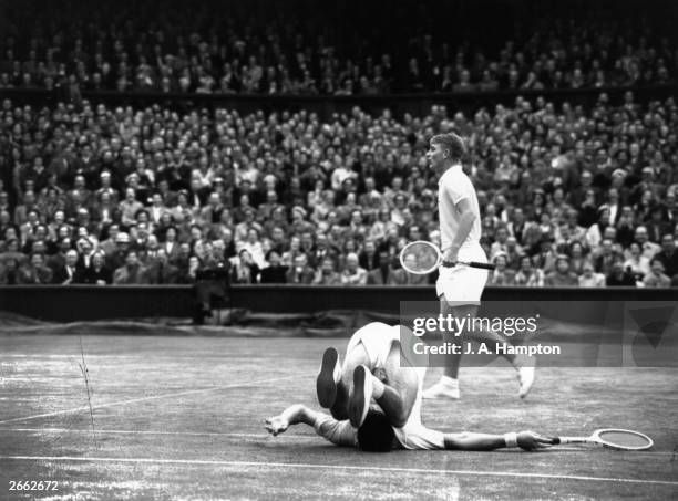 Ken Rosewall falls over backwards as fellow Australian Lew Hoad misses a shot in their doubles match against Vic Seixas and Tony Trabert at Wimbledon.