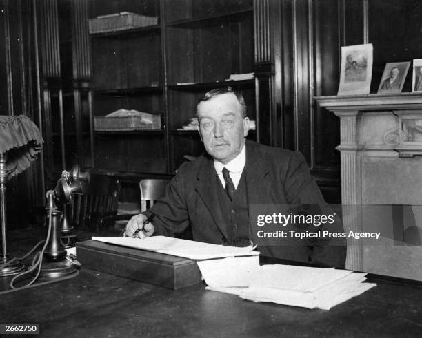 Scottish Labour politician Arthur Henderson sitting at his desk. Henderson was born in Glasgow but brought up in Newcastle where he worked as an iron...