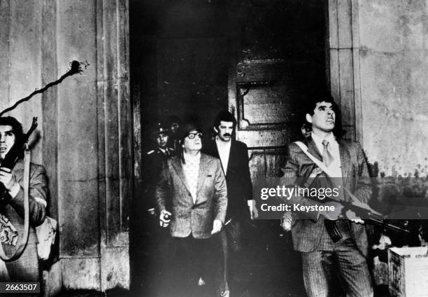 Armed guards watch out for attackers as Chilean president Salvador Allende leaves the Moneda Presidential Palace during the military coup in which he...