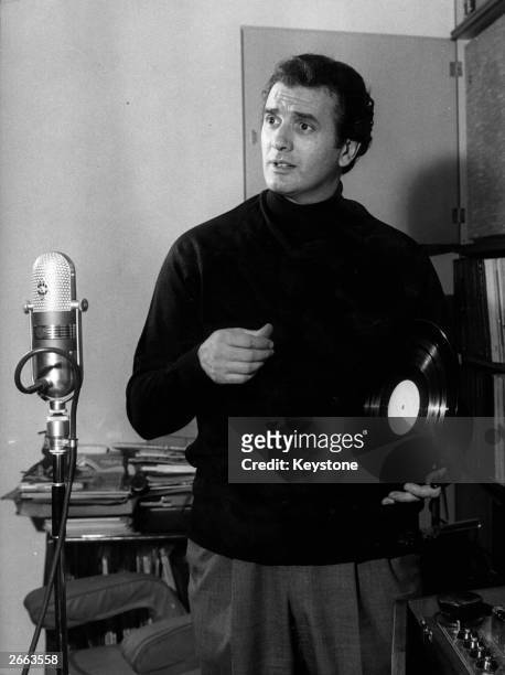 Italian opera singer Franco Corelli holding a record in front of an old fashioned microphone at his home in Milan, 9th December 1963.