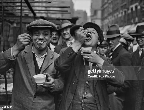 Two men enjoy jellied eels in a Whitechapel street on a Sunday morning.