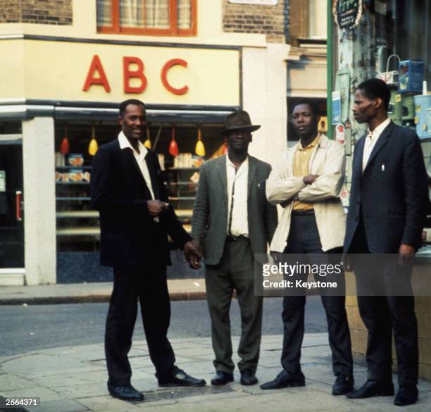 Group of four Afro-Caribbean men stand on a street corner in Notting Hill, London.