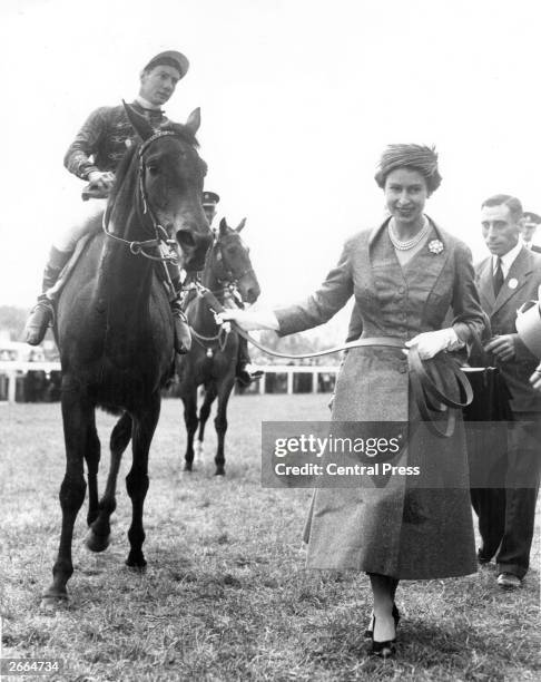 Queen Elizabeth II leads in her first classic winner, Carrozza, after the filly's victory in the Oaks at Epsom.