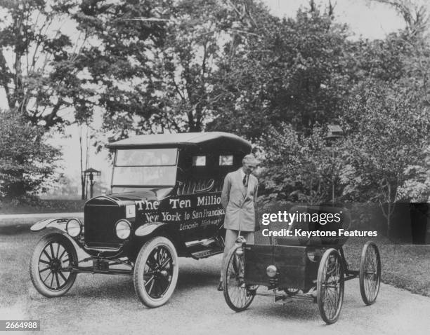 American motor vehicle industry pioneer Henry Ford standing between his first car, the Quadricycle of 1896 and the ten millionth Model-T Ford.