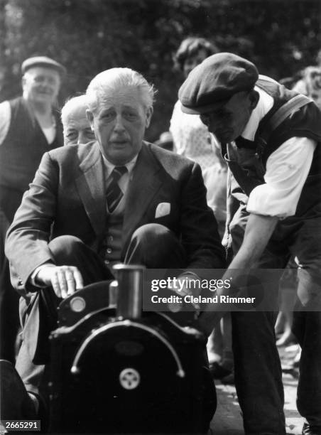 Prime Minister Harold MacMillan drives a miniature railway engine at a toy fair in Bromley, Kent where he is their local MP.