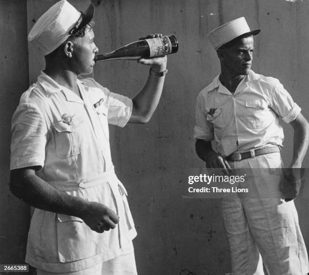 Two men of the French Foreign Legion, one drinking wine from a bottle, on leave in Saigon.