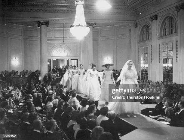 Mannequins walking down the 64 foot catwalk during the grand finale of Christian Dior's 1955 fashion show at a ball in Gleneagles. The designer...