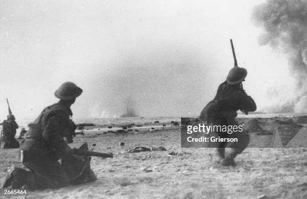 British soldiers fight a rearguard action during the evacuation at Dunkirk, shooting rifles at attacking aircraft. Bombs are exploding in the sea.