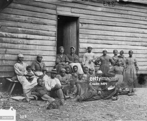Group of escaped slaves outside a cabin. Escaped slaves were known as contrabands after the Union General Benjamin Butler announced that any slaves...