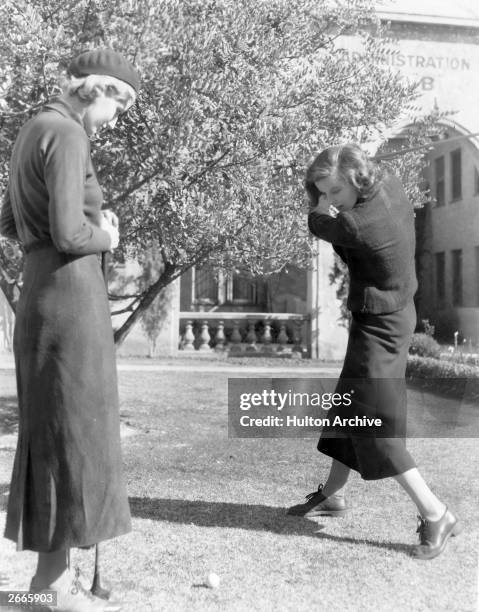 American actress Katharine Hepburn plays a game of golf with a friend.