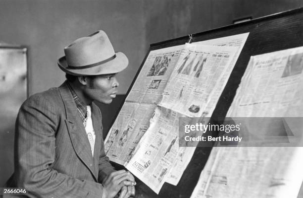 West Indian immigrant reading a newspaper in a Liverpool library. Original Publication: Picture Post - 4825 - Is There A British Colour Bar? - pub....