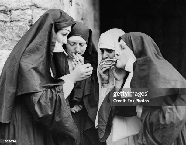 Women dressed as nuns have a cigarette break during the Walmer Castle pageant in Kent.