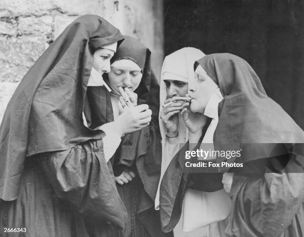 Women dressed as nuns have a cigarette break during the Walmer Castle pageant in Kent.