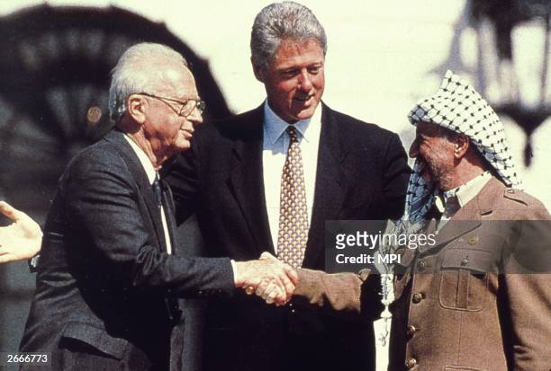 American President Bill Clinton watches as the Israeli Prime Minister Yitzhak Rabin shakes hands with the Palestinian leader Yasser Arafat in the...
