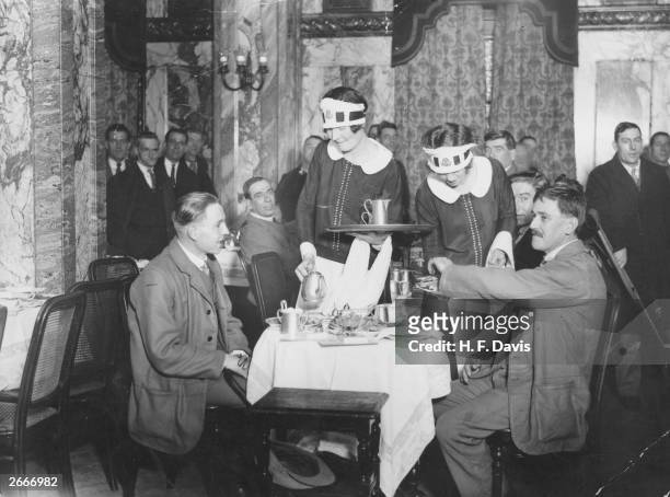 Nippies, waitresses for Lyon's Corner House Tea Rooms, serve some of the 1,000 disabled soldiers being entertained with tea at Coventry Street Corner...