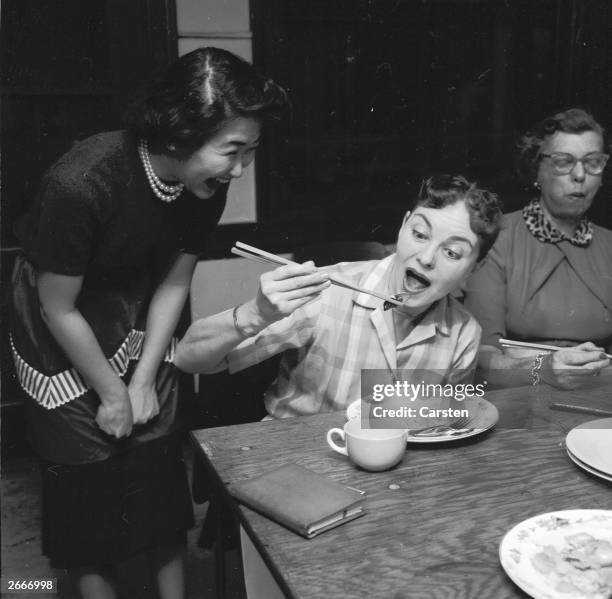 One of Calvin Lee's pupils attempts to pick up a mussel with a pair of chopsticks, much to the amusement of her teacher, during a class in Chinese...