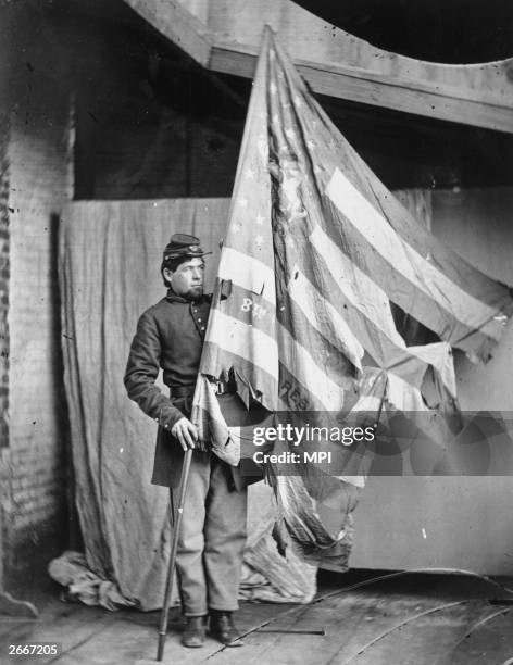 Soldier holding up the torn flag of the 8th Pennsylvania Reserve Colour Guard during the American Civil War.