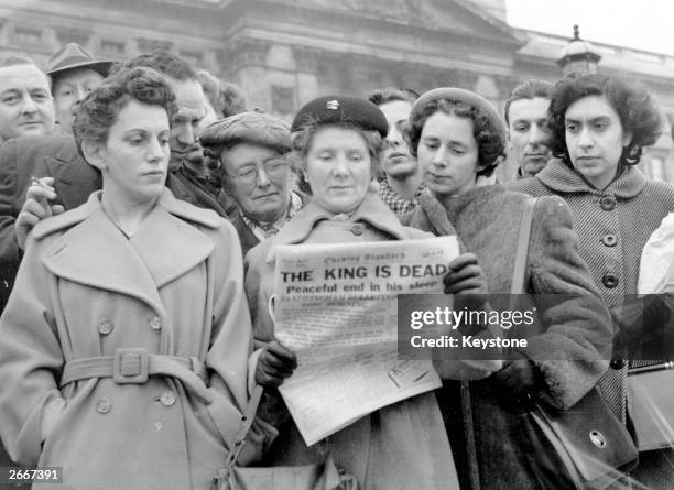 Crowds outside Buckingham Palace, London, reading the news in the Evening Standard newspaper that King George VI had died at Sandringham, 6th...