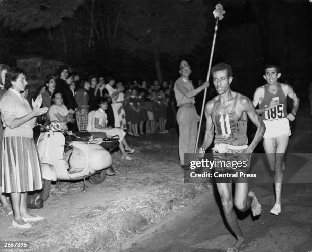 Abebe Bikila of Ethiopia, running barefoot, draws away from Abdesselem Rhadi of Morocco near the finish of the marathon at the 1960 Rome Olympics. He...
