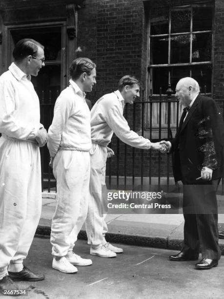 British athlete Roger Bannister shakes hands with Prime Minister Winston Churchill outside Downing Street in London, as fellow runners Chris Brasher...