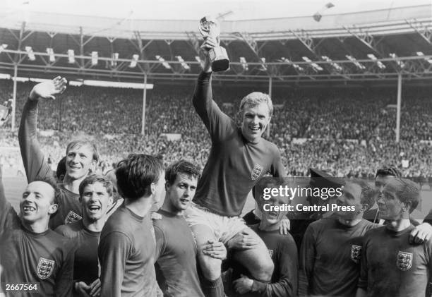 England captain Bobby Moore holds up the Jules Rimet trophy as he is carried on the shoulders of his team-mates after their 4-2 victory over West...