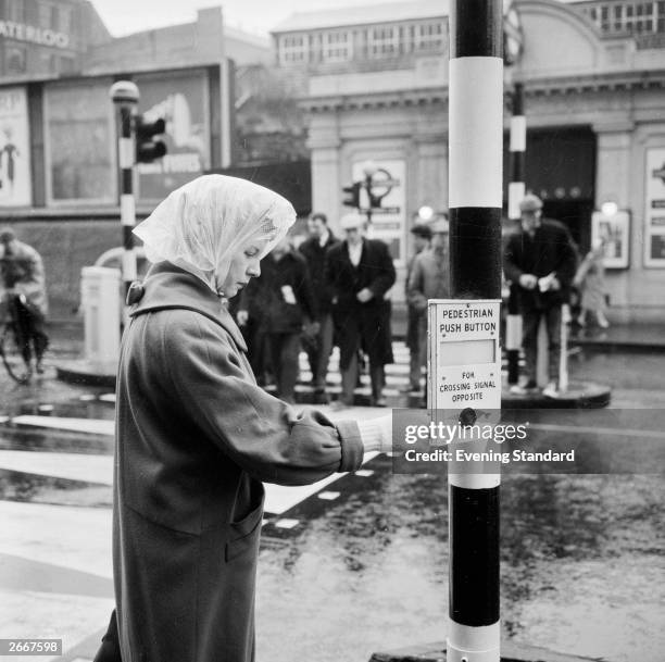 Woman pressing the button at a panda crossing near Waterloo Station.